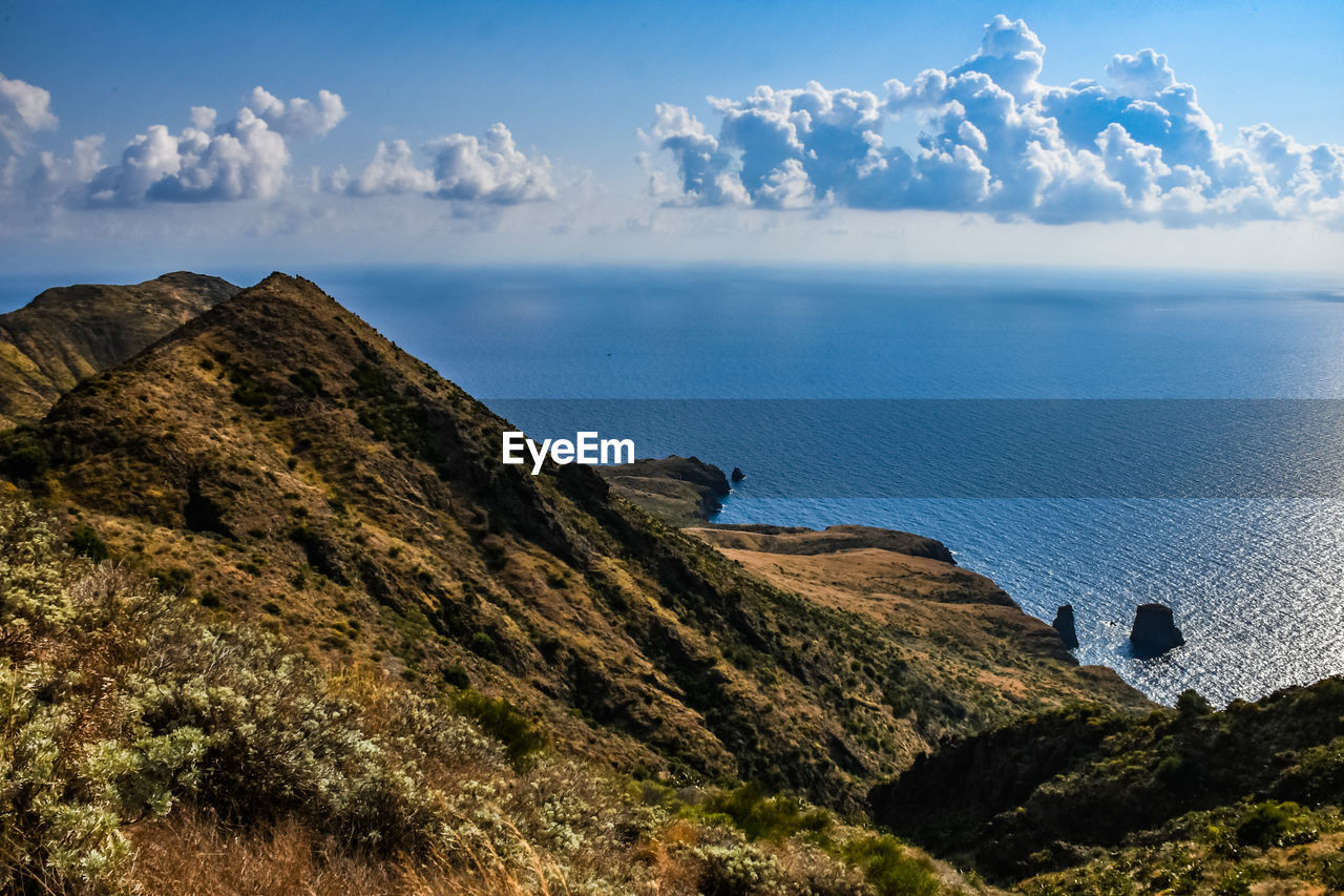 SCENIC VIEW OF SEA BY MOUNTAINS AGAINST SKY