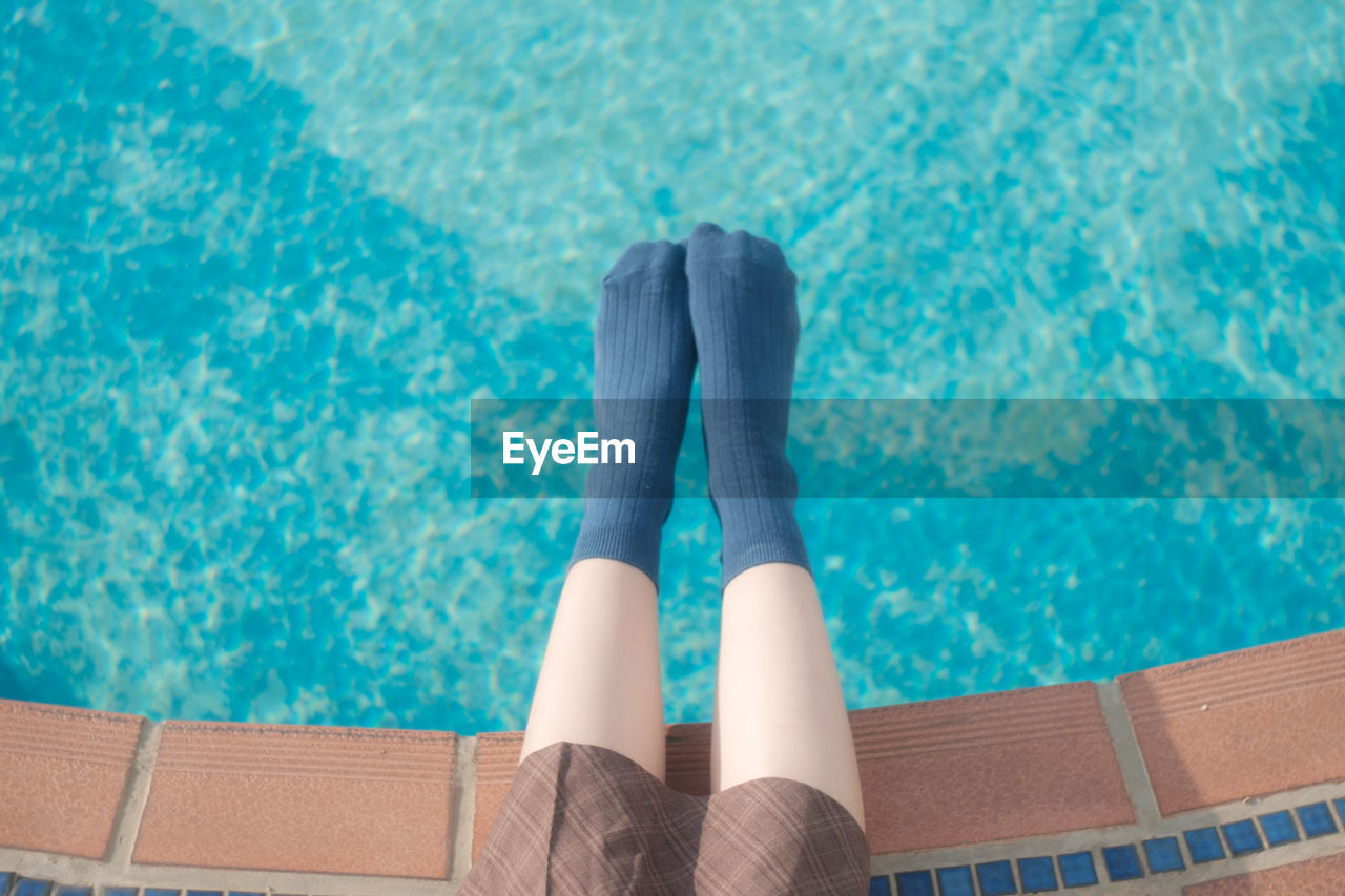 Low section of woman relaxing by swimming pool