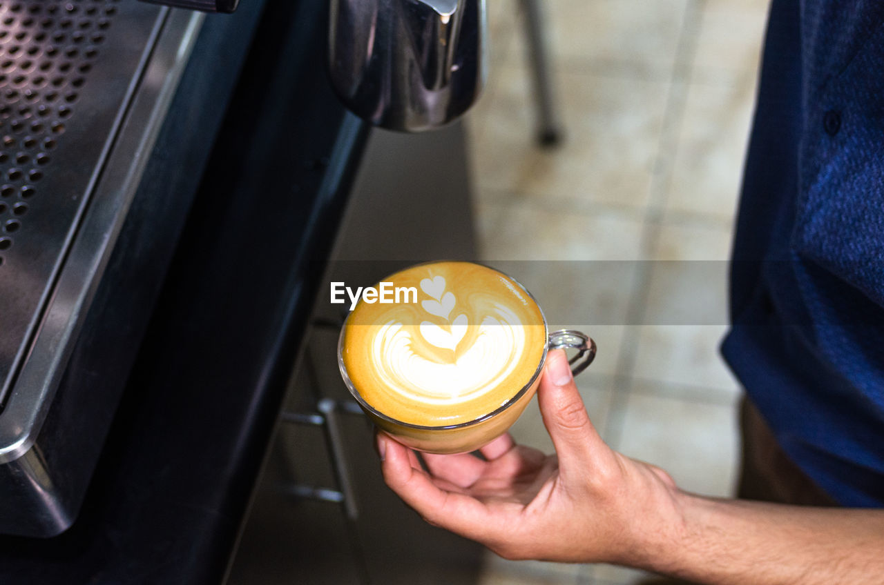 HIGH ANGLE VIEW OF HAND HOLDING COFFEE