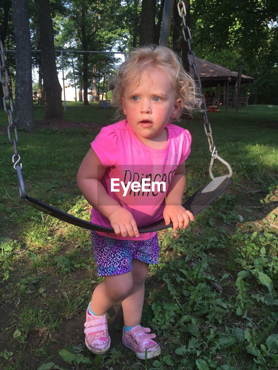 Cute girl standing by swing in playground