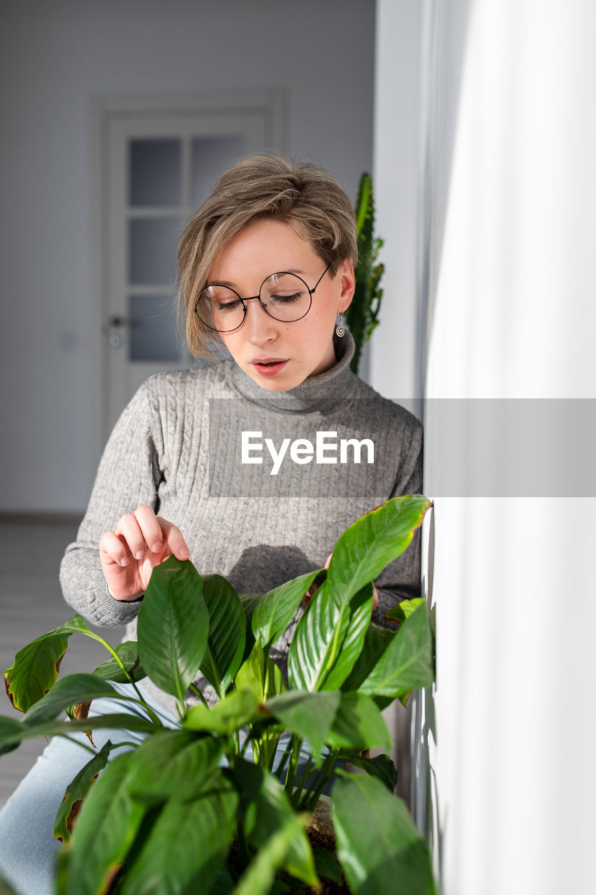 Woman touching plant at home