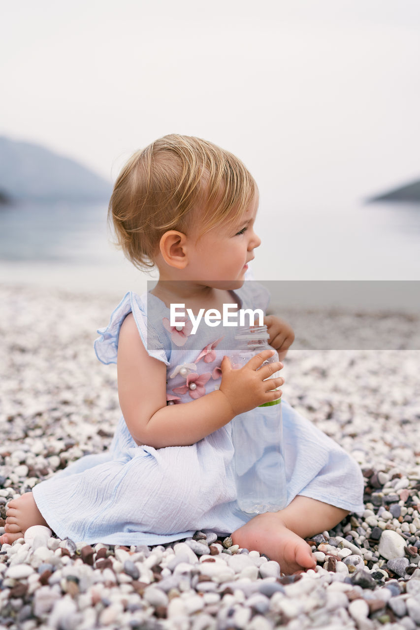 Cute girl sitting on pebbles at beach