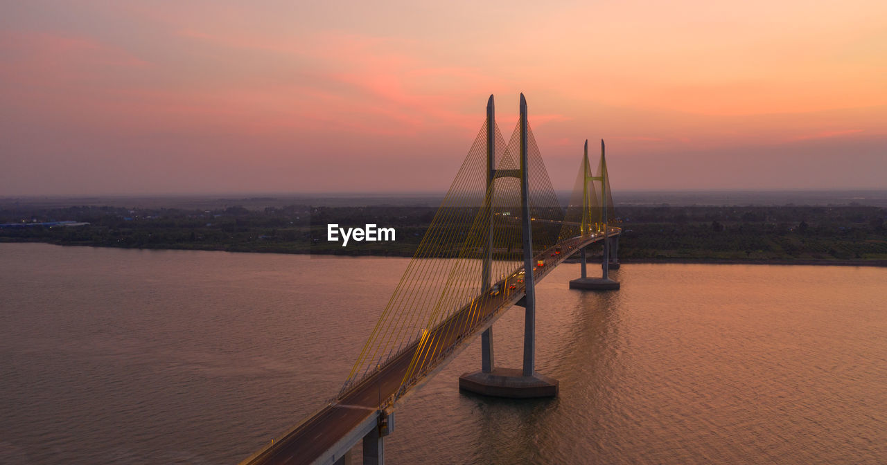 Bridge over river against romantic sky at sunrise