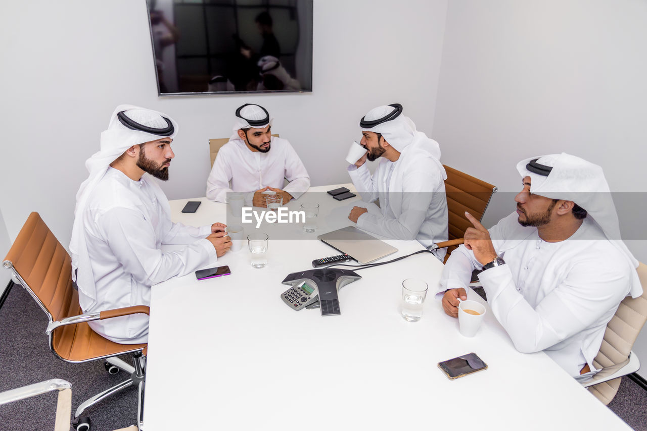 GROUP OF PEOPLE SITTING ON TABLE IN OFFICE