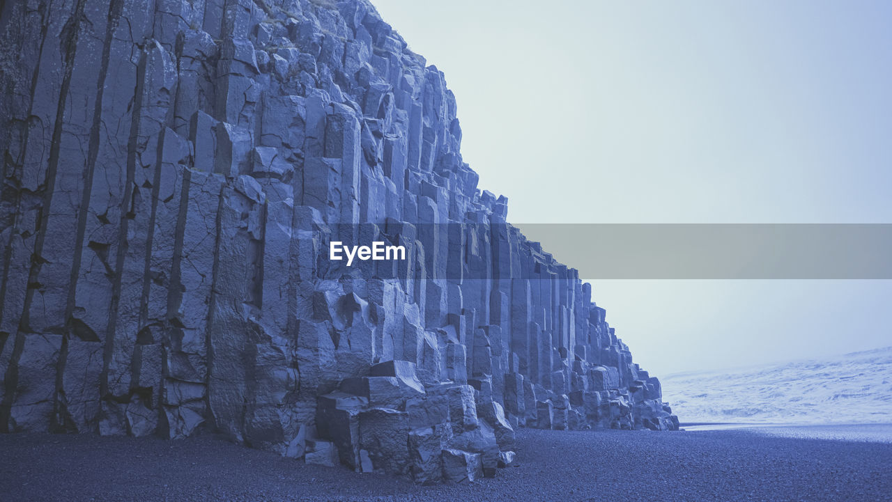 Rock formations on snow covered mountain against sky