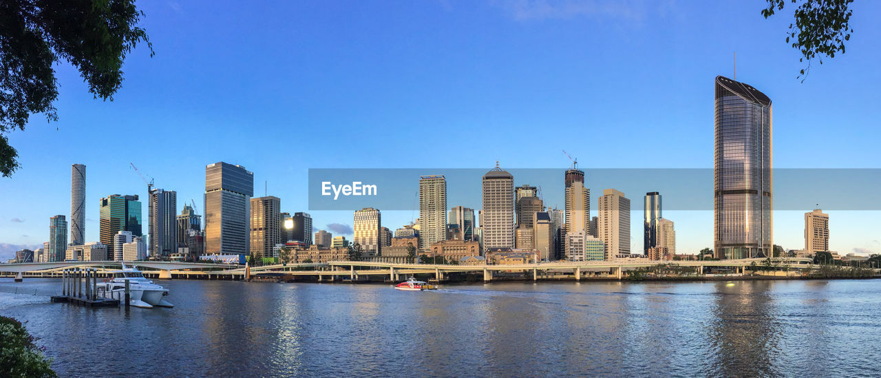 Brisbane river and buildings in city against clear sky