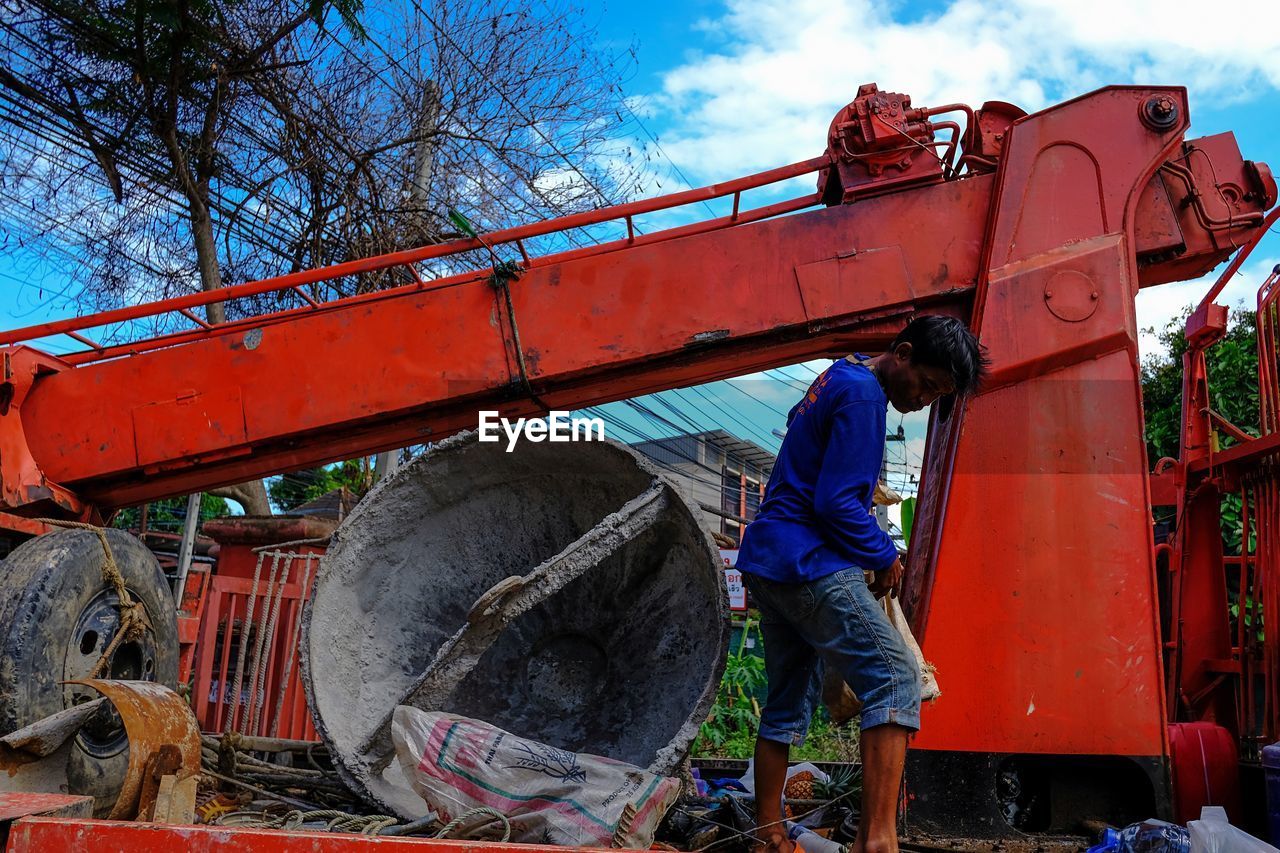 Man working by machinery against sky
