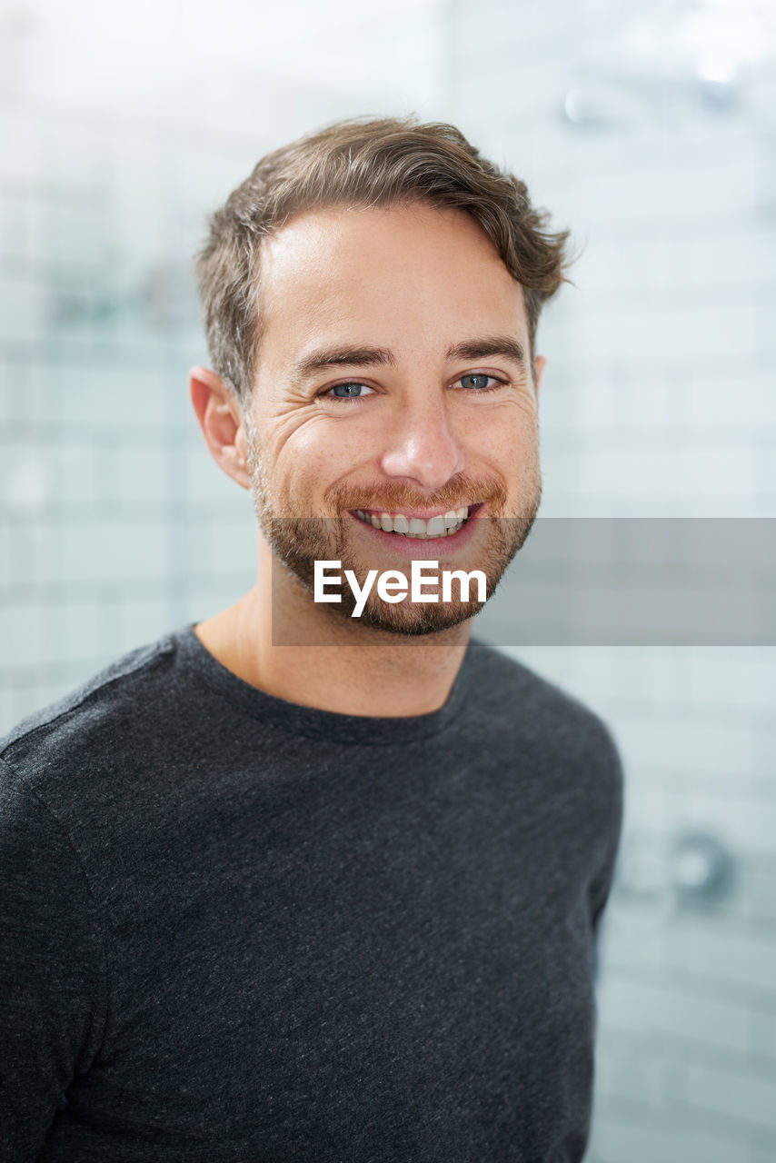 smiling, portrait, one person, happiness, adult, beard, men, looking at camera, facial hair, emotion, person, human hair, casual clothing, smile, teeth, cheerful, indoors, human face, young adult, headshot, front view, portrait photography, hairstyle, standing, business, sweater, focus on foreground, clothing, waist up, businessman, stubble, office, brown hair, business finance and industry, day