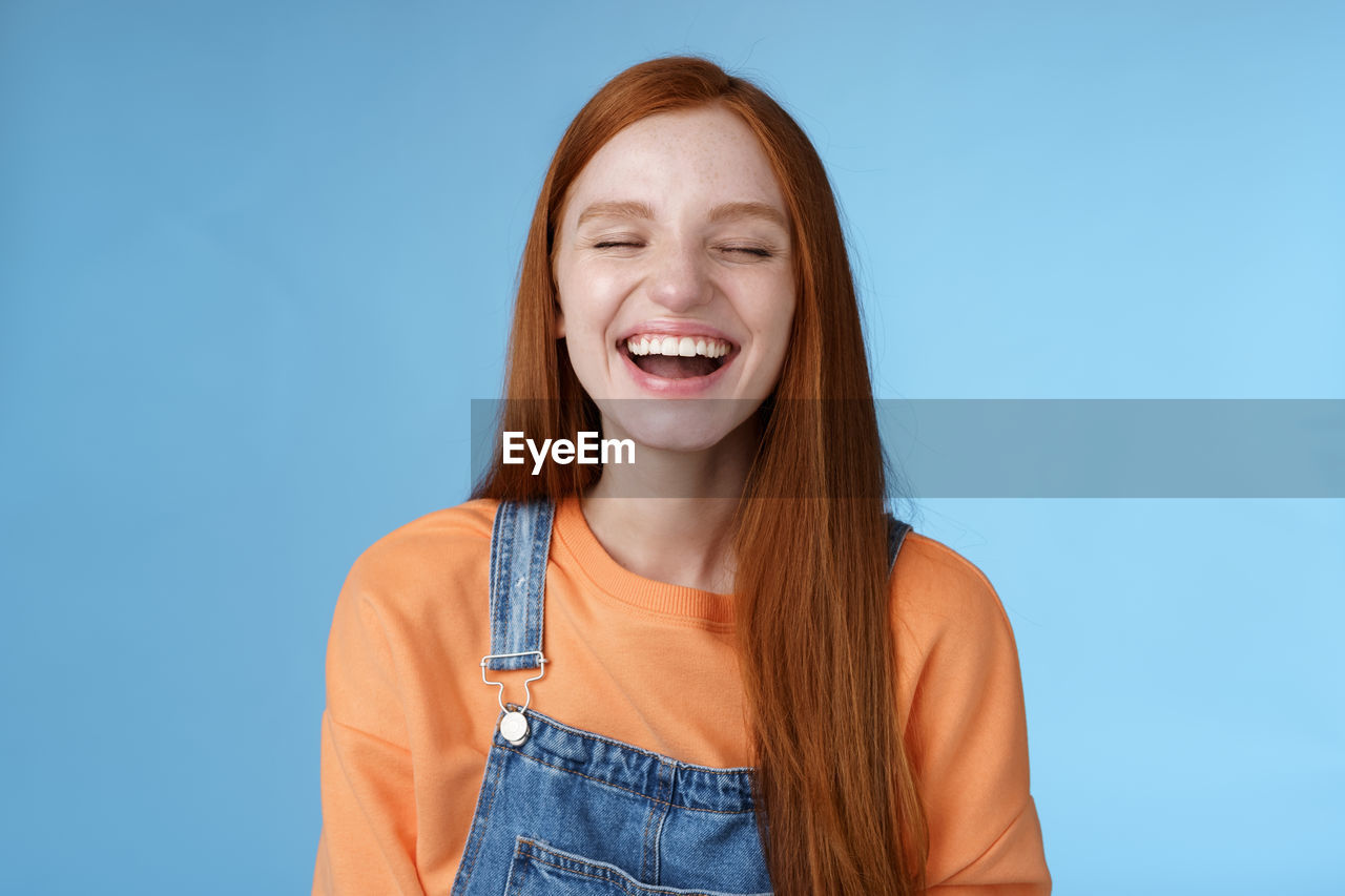 Redhead woman laughing against blue background