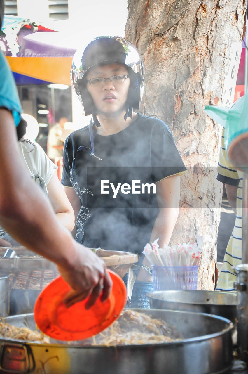 Low angle view of woman wearing helmet looking at food while standing on street