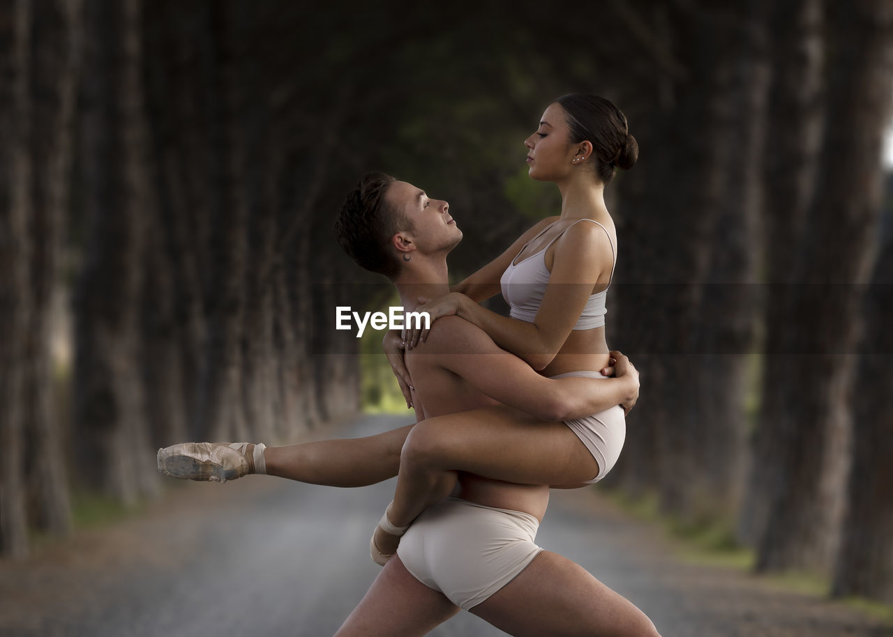 Couple dancing in road amidst tree