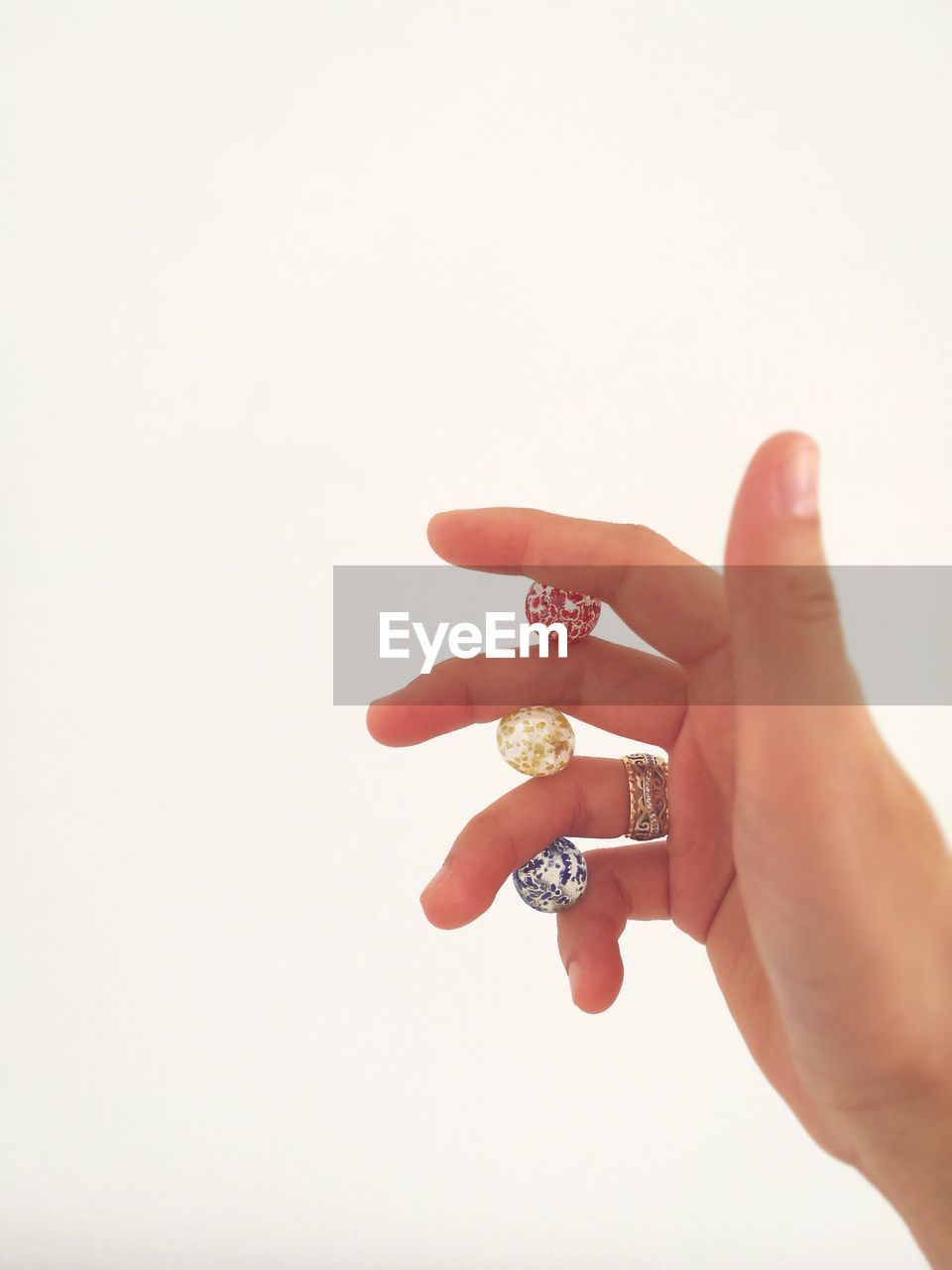 Cropped image of hand holding beads against white background