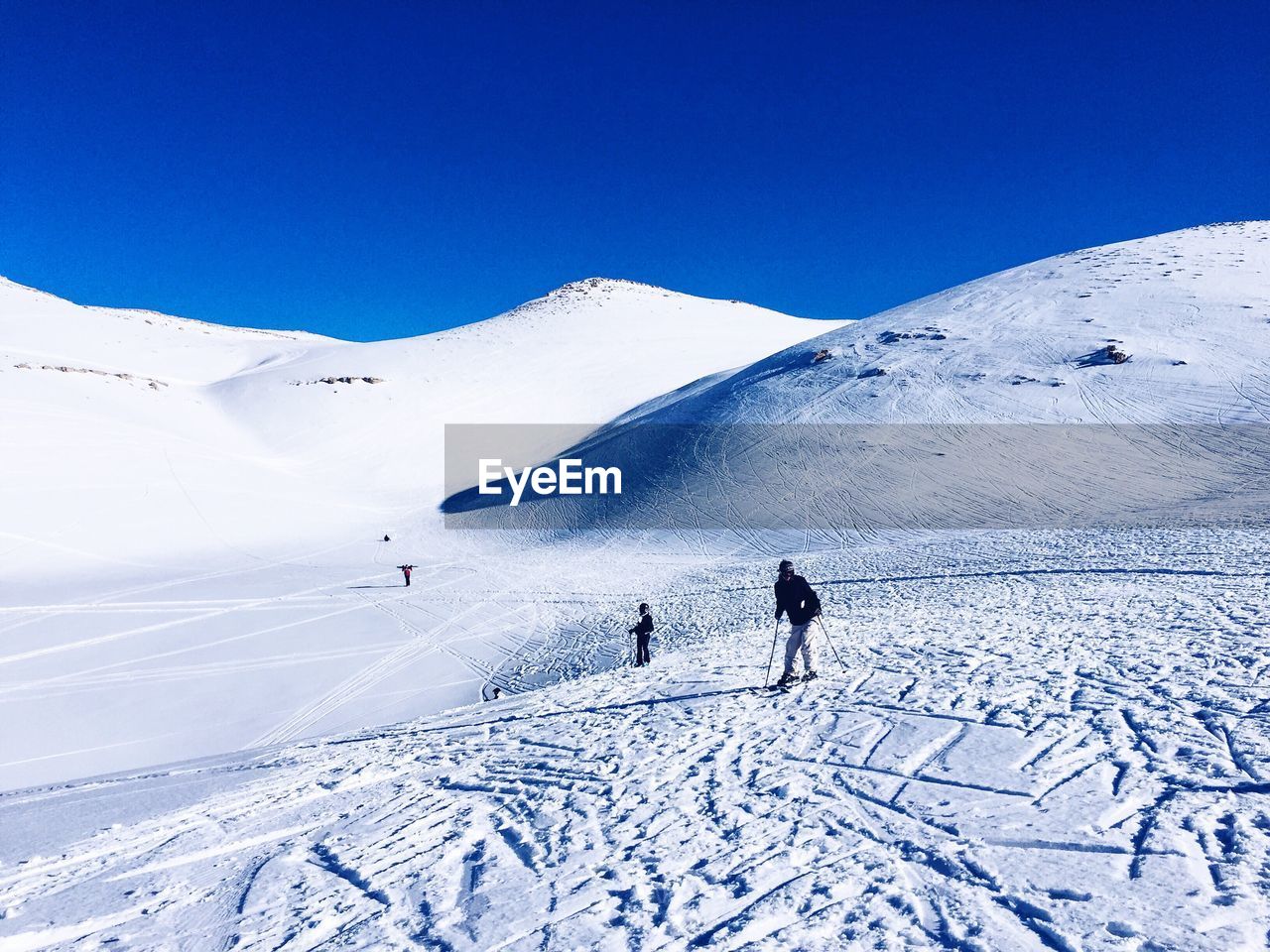 People skiing on snowy field against sky