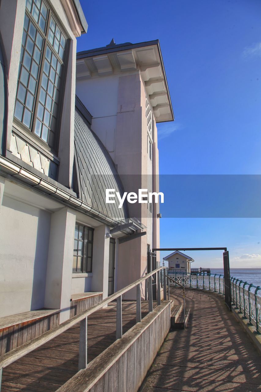 Building by sea against clear blue sky