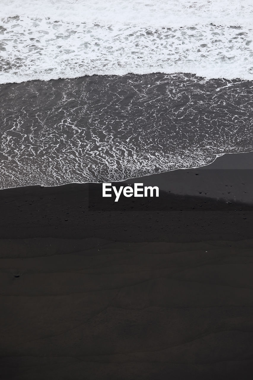 Waves on black sand beach with copy space. beauty in nature in tenerife. canary islands, spain.