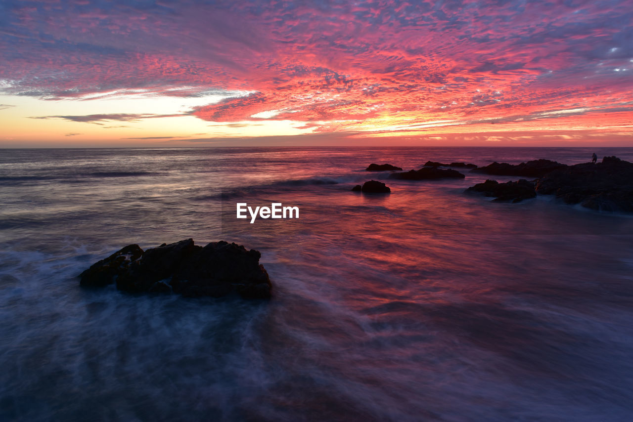 Scenic view of sea against cloudy sky during sunset
