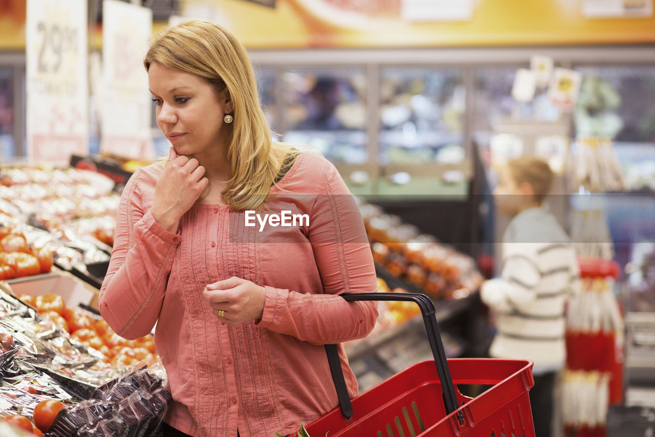 Thoughtful woman shopping vegetables in grocery store