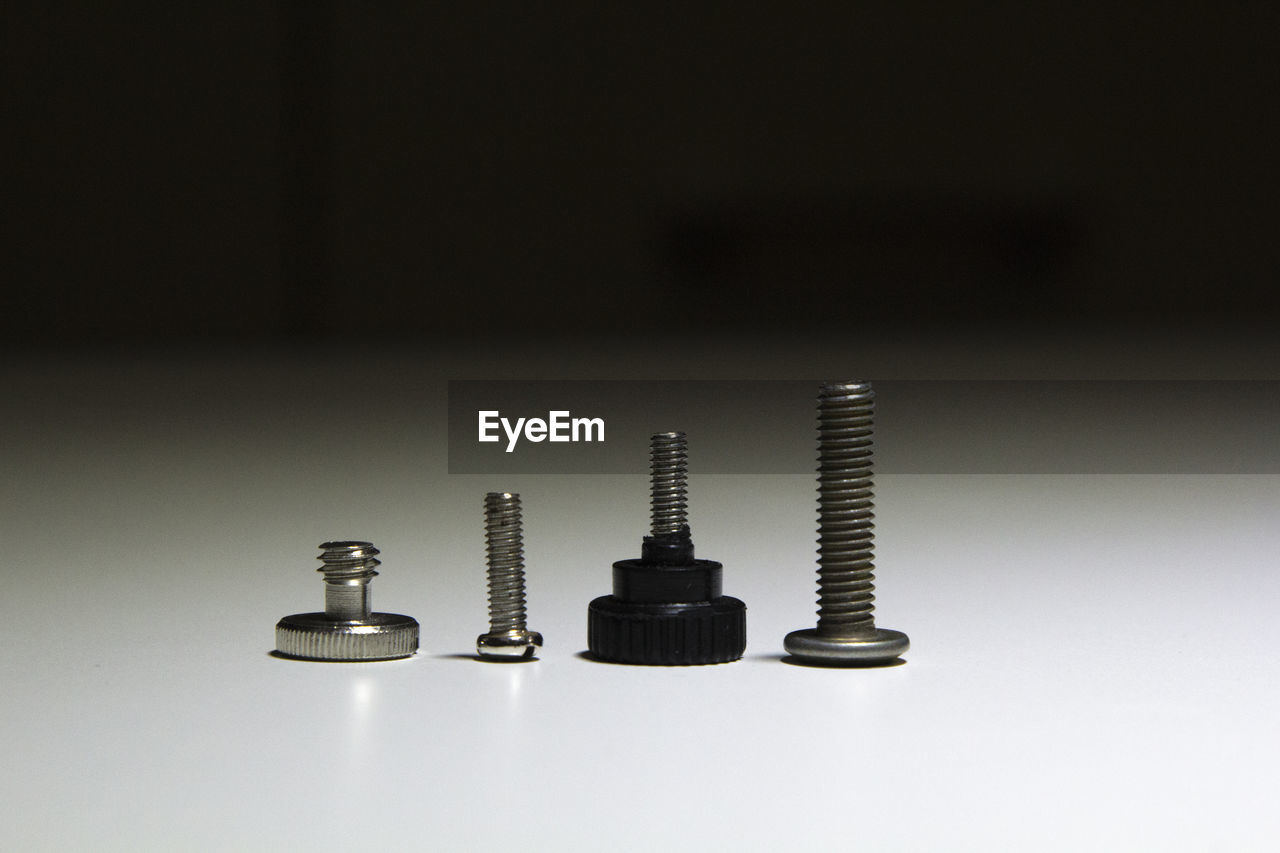 Close-up of various bolts on table against black background