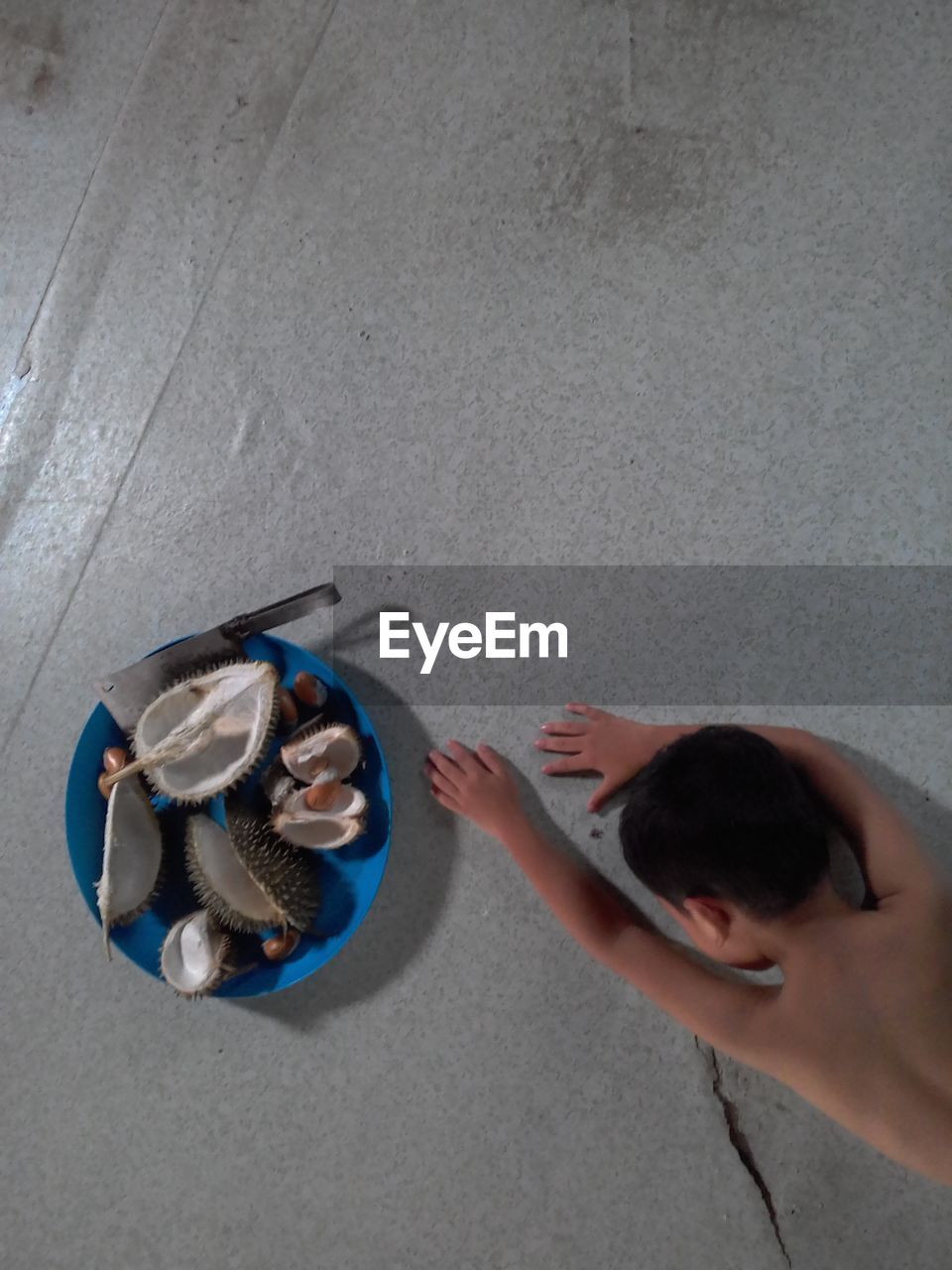 High angle view of shirtless boy lying by food on floor