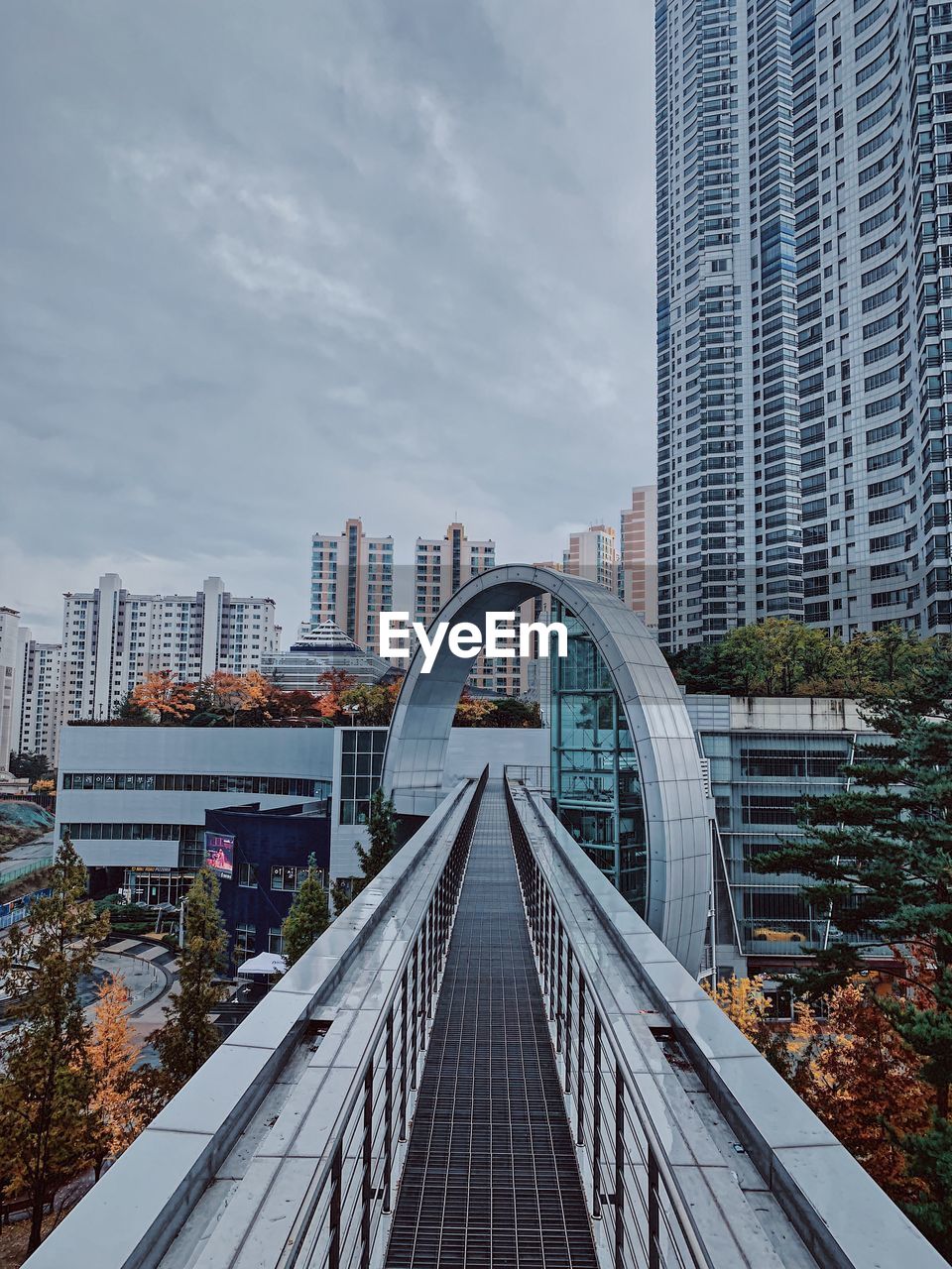 High angle view of elevated walkway leading towards buildings in city against sky