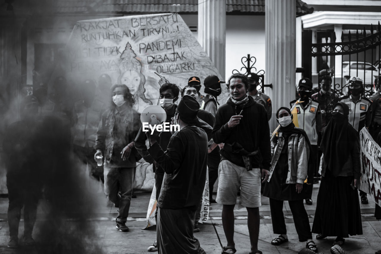 REAR VIEW OF PEOPLE STANDING ON STREET