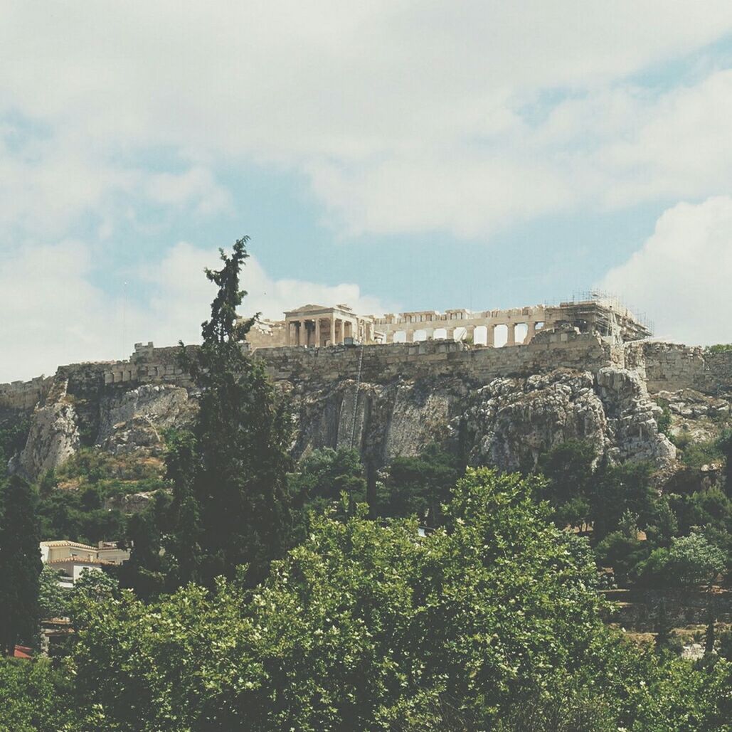 Low angle view of parthenon on hill against cloudy sky