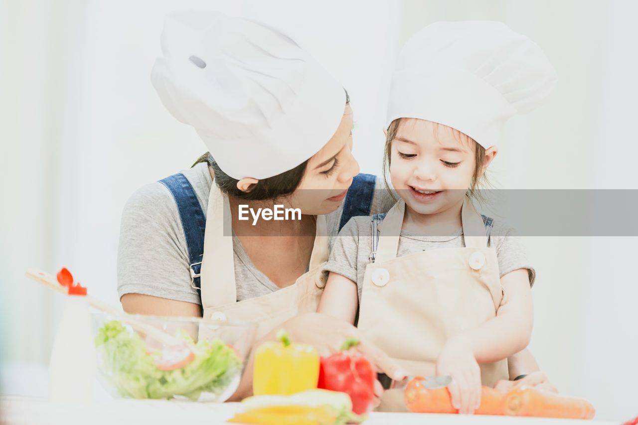Mother and daughter preparing food on table