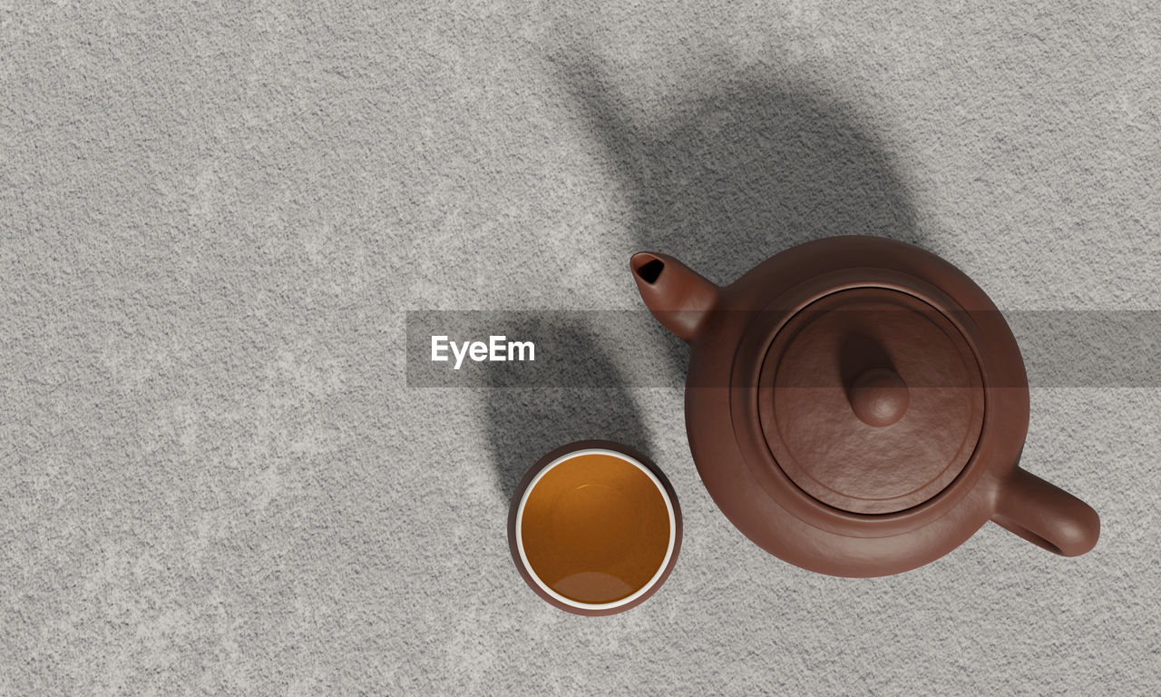 Brown clay teapot and a teacup or clay teacup, white inside with golden yellow tea.
