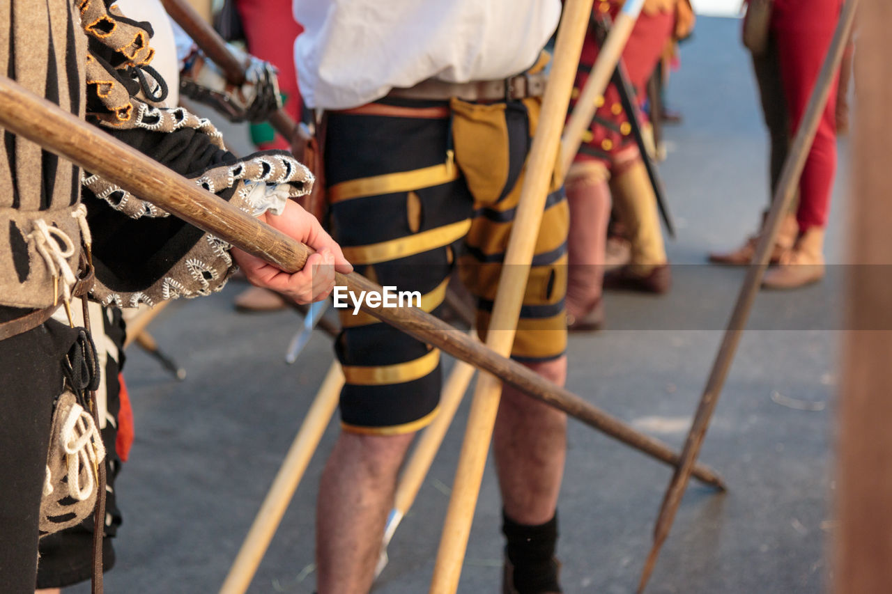 Low section of people standing with spear on road