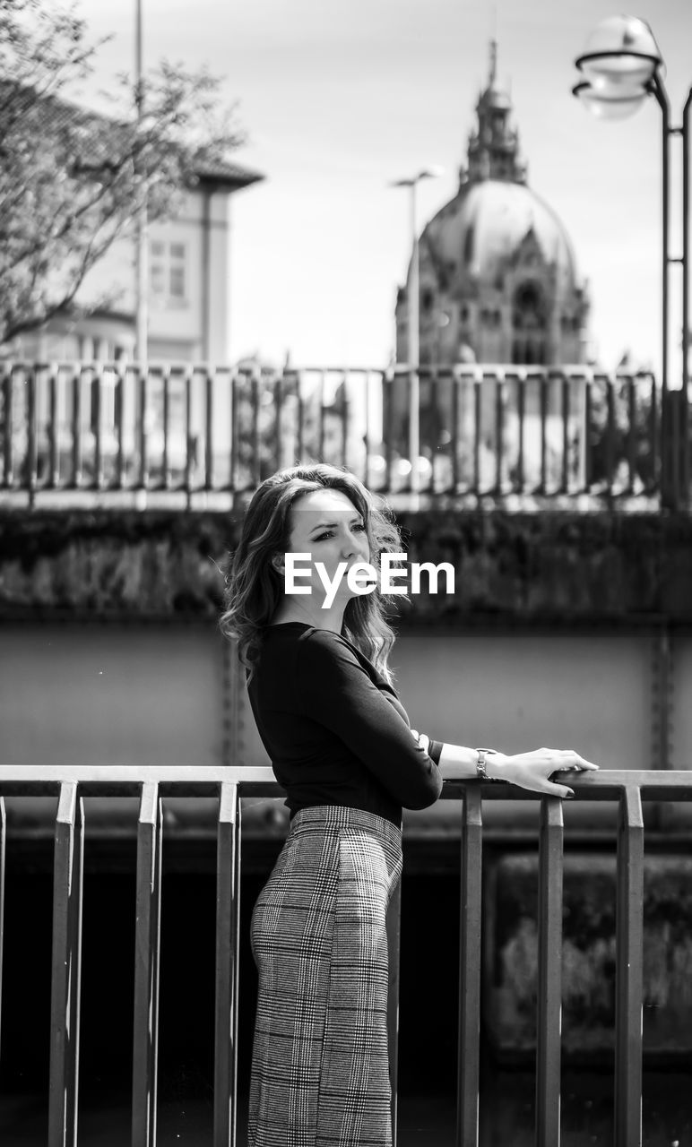 Woman standing against railing in city