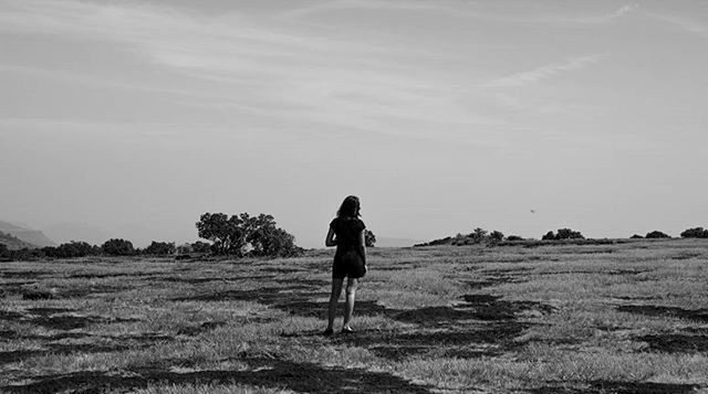 WOMAN STANDING ON GRASSY FIELD