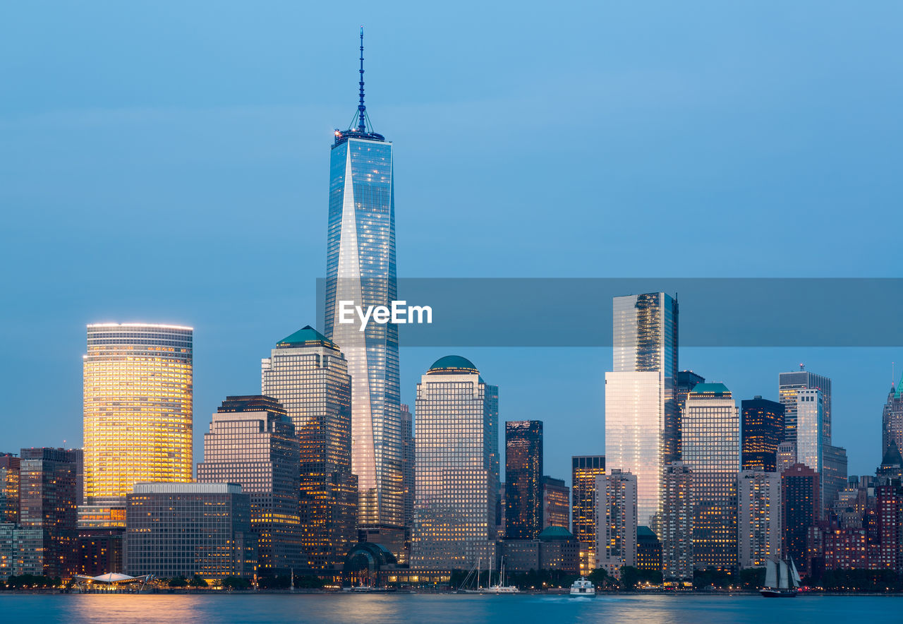 Illuminated lower manhattan buildings by hudson river