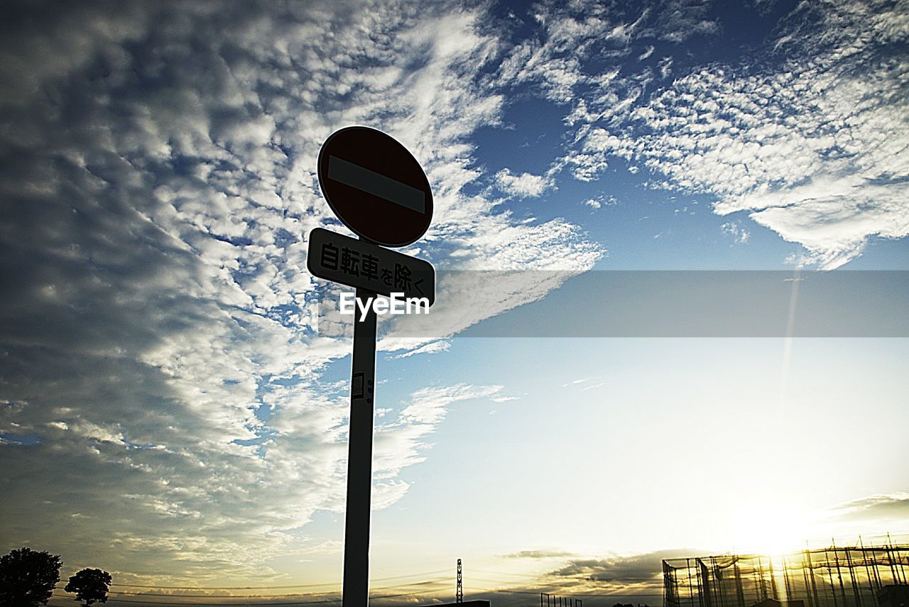 Low angle view of silhouette road sign against sky at sunset