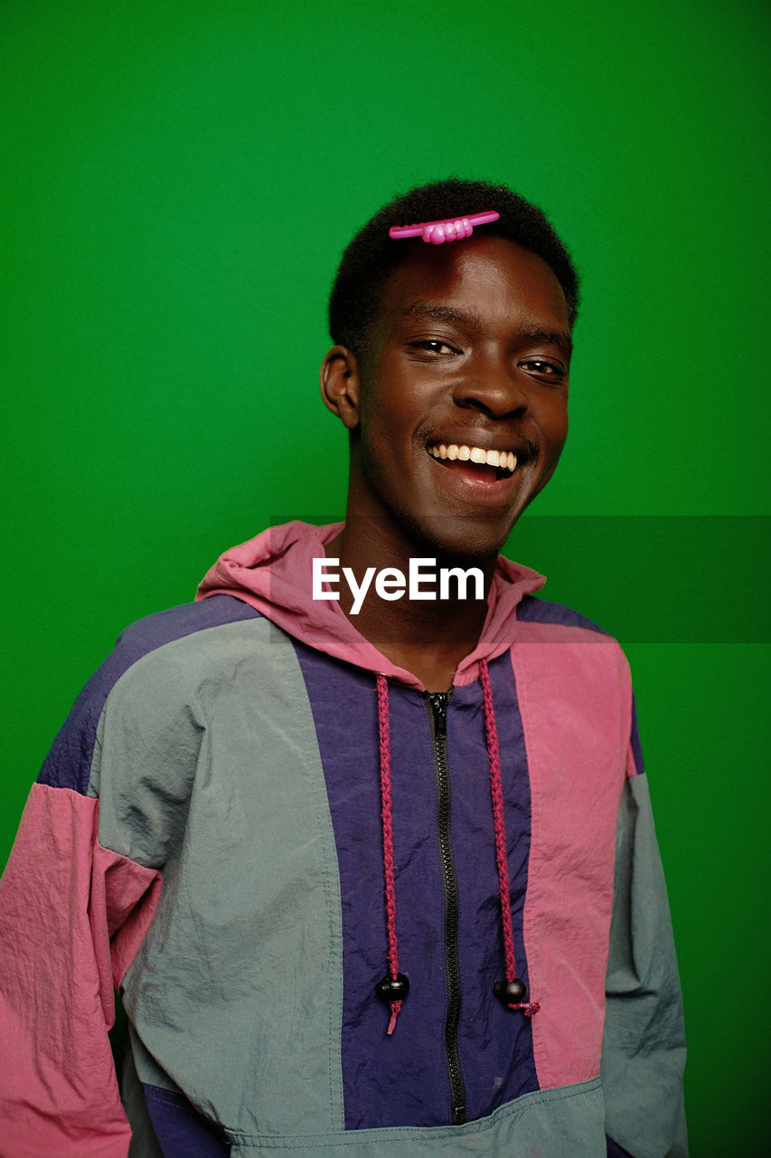 Portrait of young man standing against green background