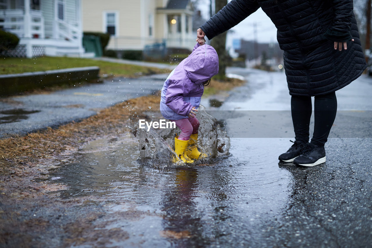 A little girl having fun splashing in puddles on a rainy day.