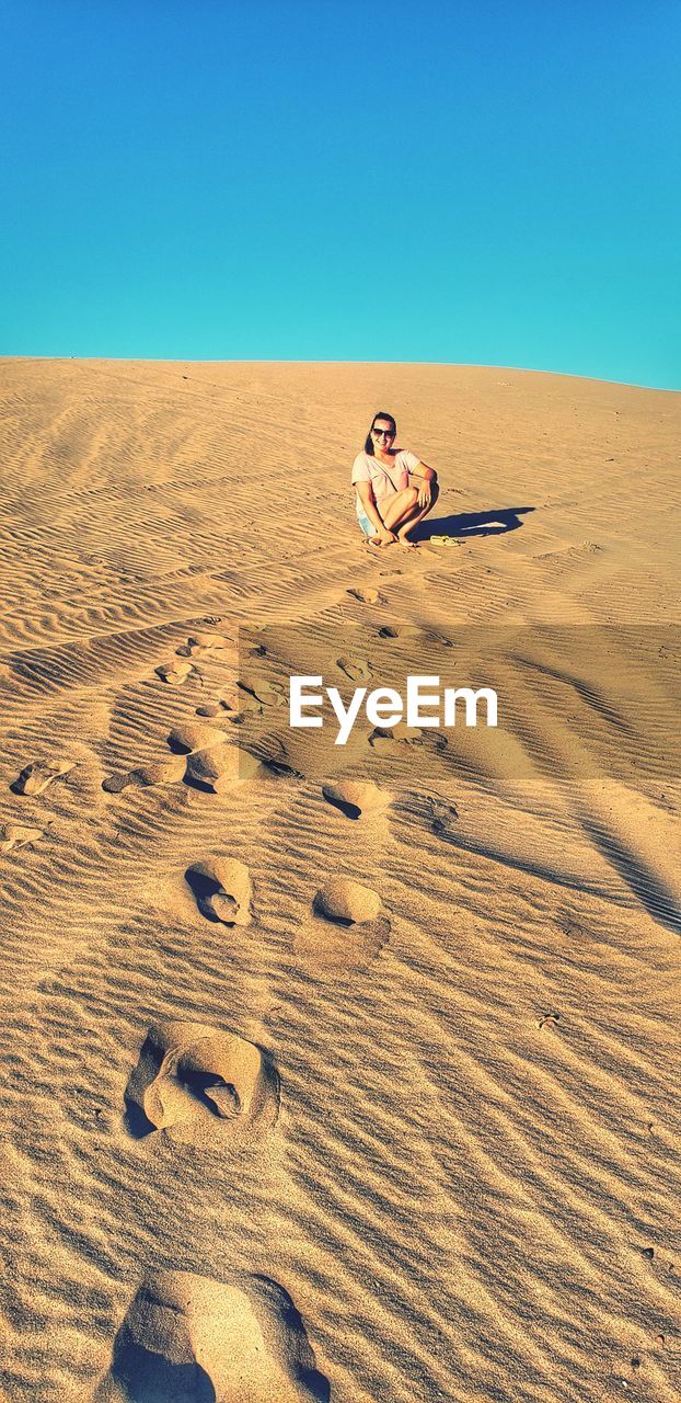 SHADOW OF PERSON ON SAND DUNE IN DESERT