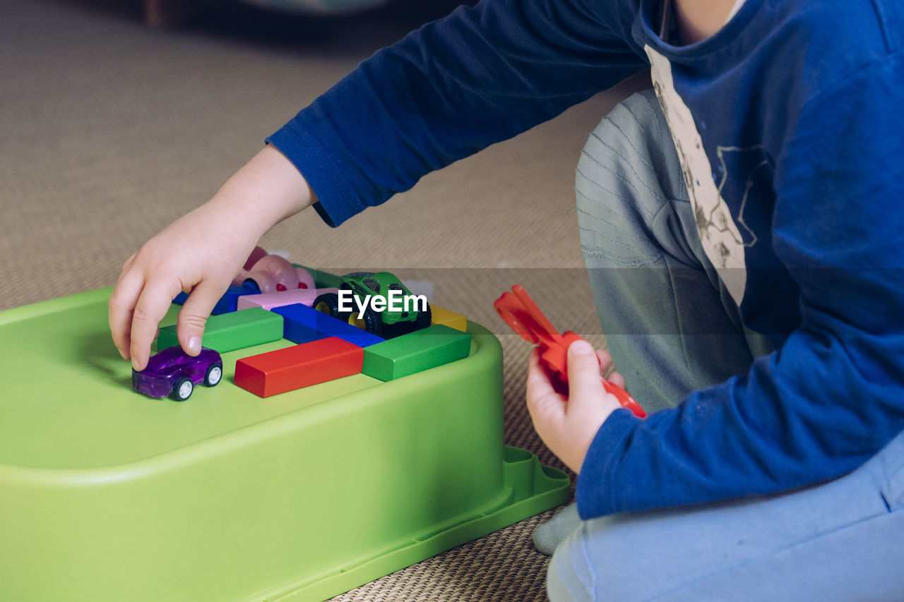 High angle view of boy playing with tattoo on table