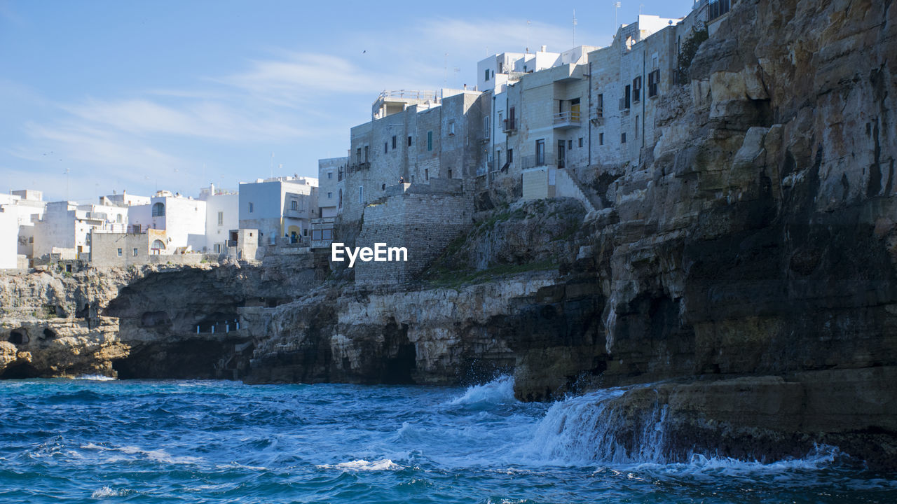 Scenic view of buildings on cliff by sea