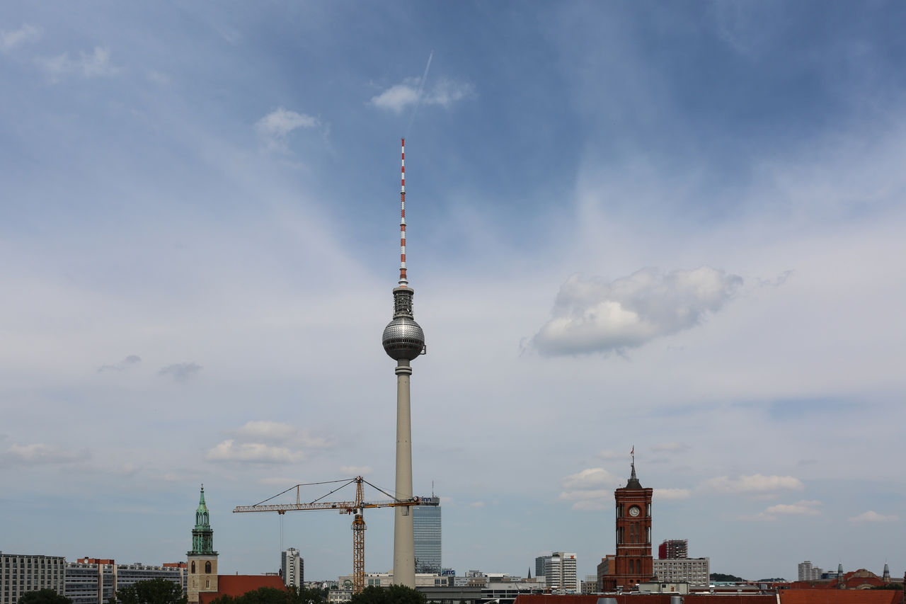 Communications tower in city against sky