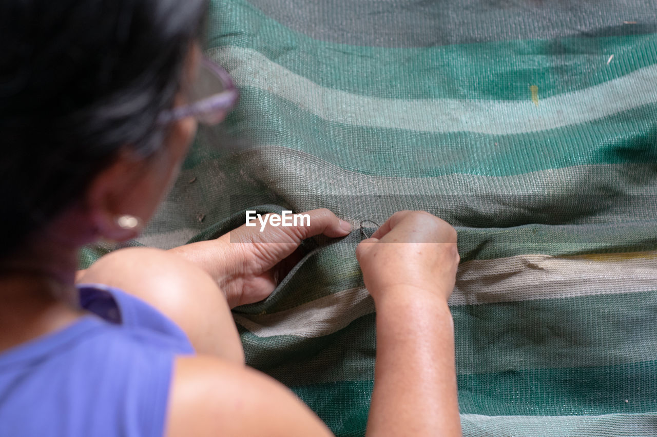 High angle view of woman stitching textile