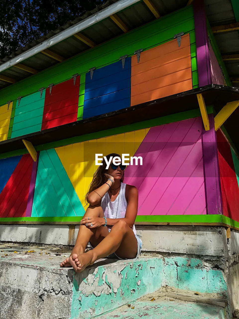Full length of woman sitting against colorful built structure