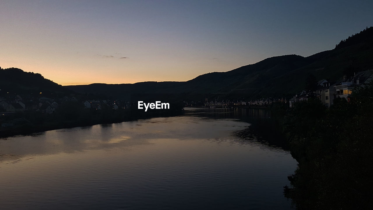 SCENIC VIEW OF LAKE BY SILHOUETTE MOUNTAINS AGAINST CLEAR SKY