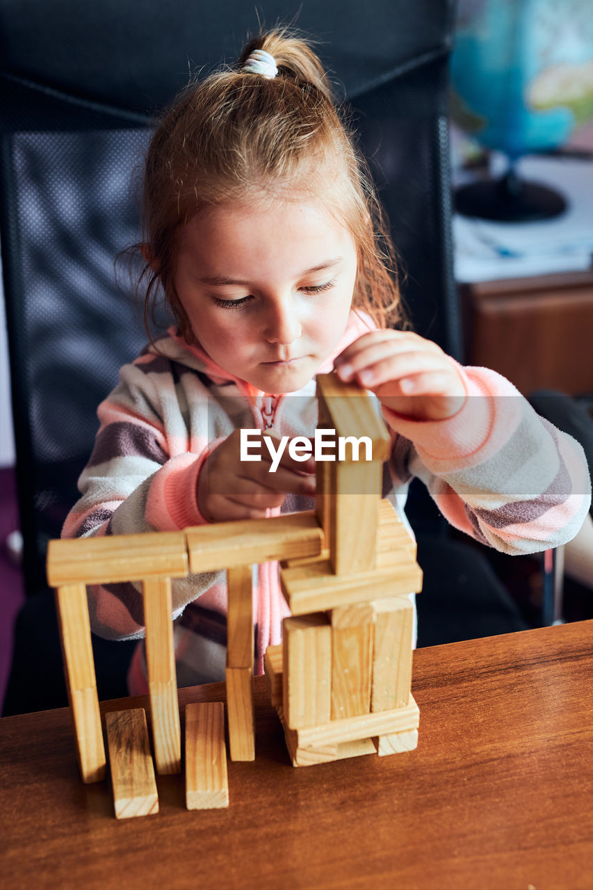 GIRL PLAYING WITH TOY ON TABLE