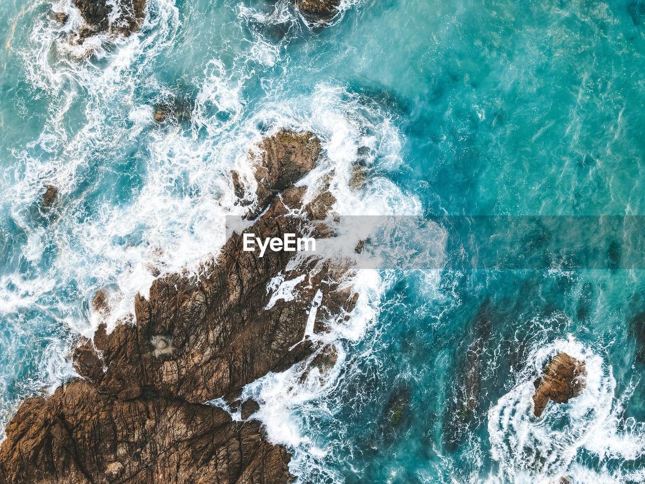 HIGH ANGLE VIEW OF WAVES SPLASHING ON ROCK