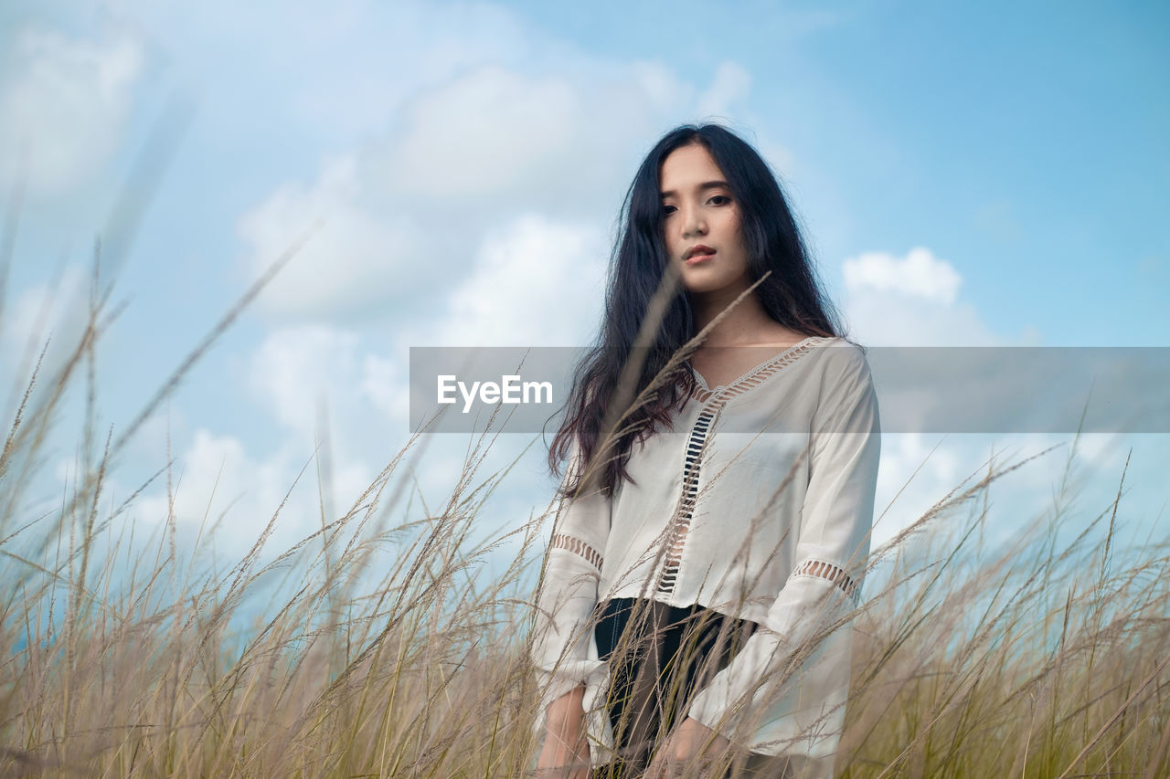 Asian long hair girl in white clothes enjoys life in nature coastal field.