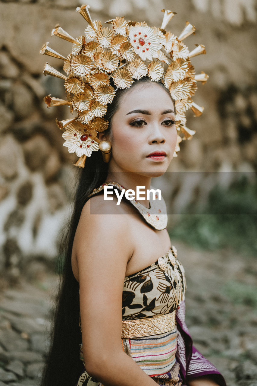 portrait of young woman standing against trees