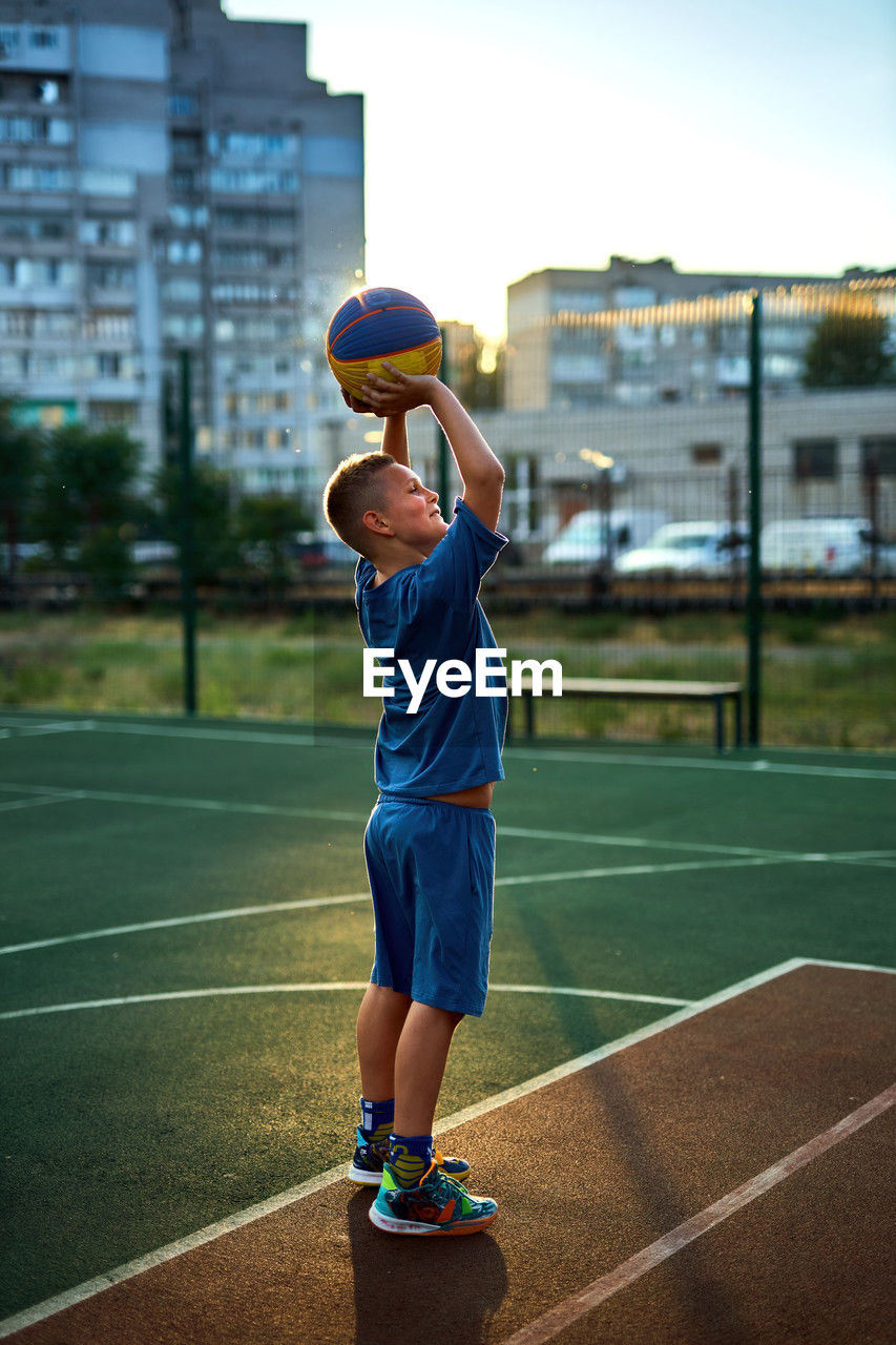 Sports and basketball. boy in a blue tracksuit throwing a basketball ball into the hoop 