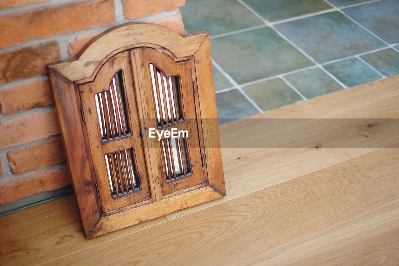 High angle view of small wooden door on table against brick wall