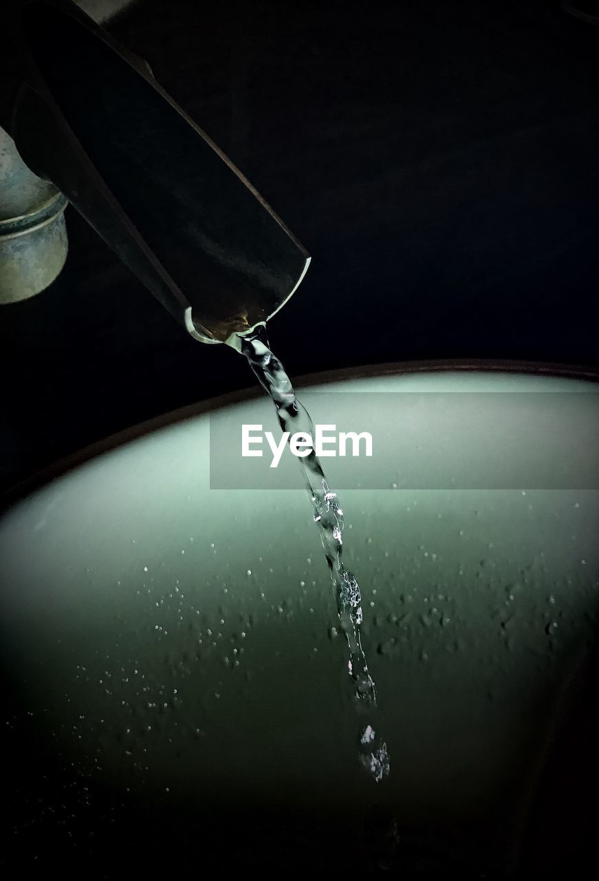 High angle view of water flowing in container over black background