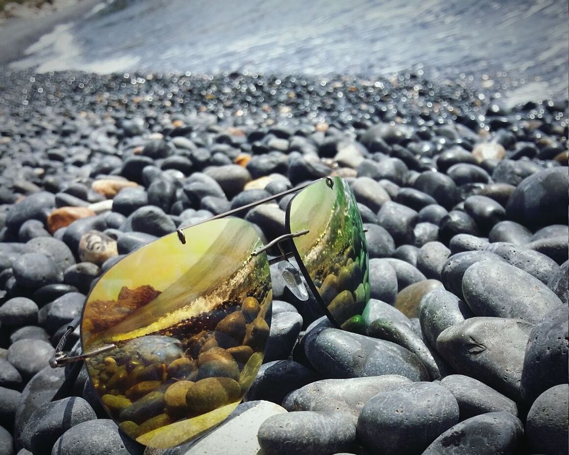 Close-up of sunglasses on pebbles at shore